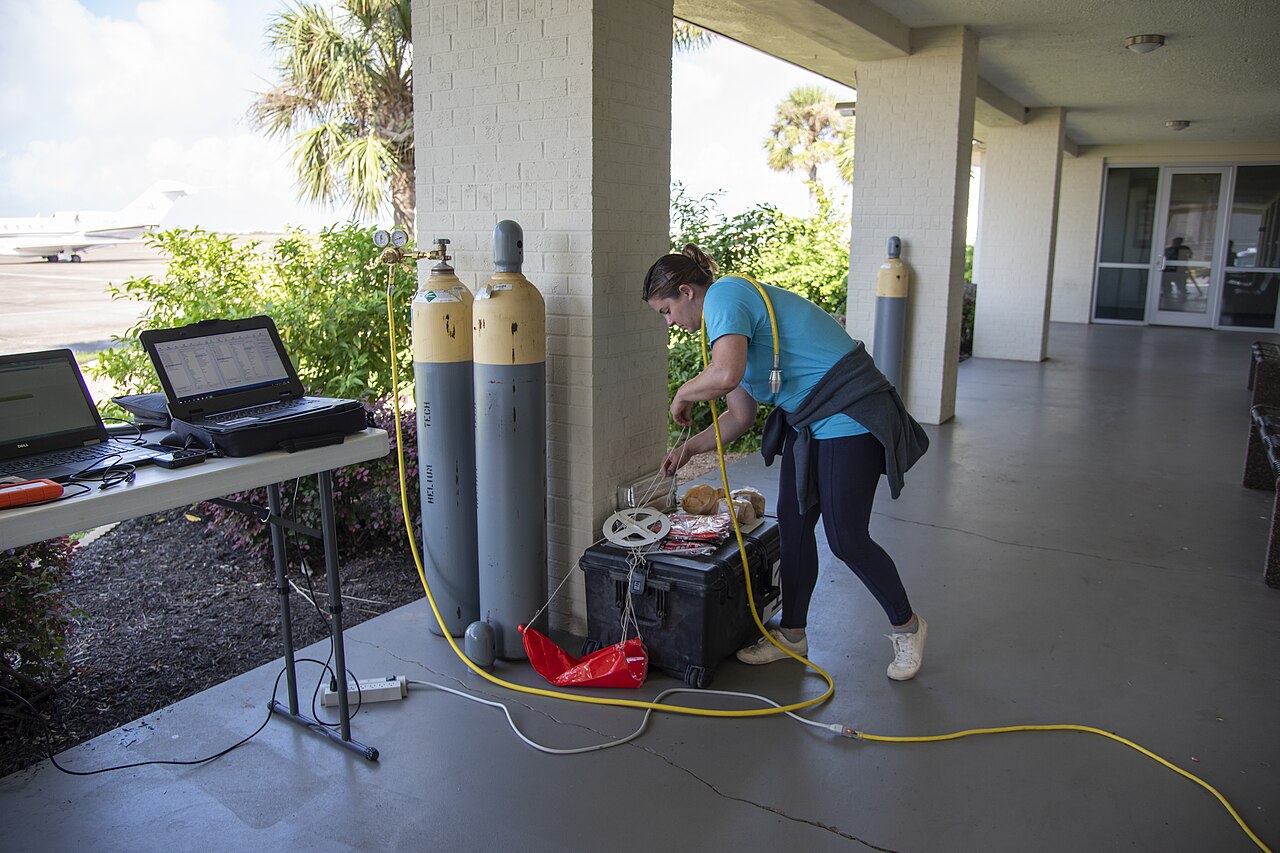 A meteorologist filling a weather observation balloon with helium — a symbol of WindBorne's direct-observation strategy