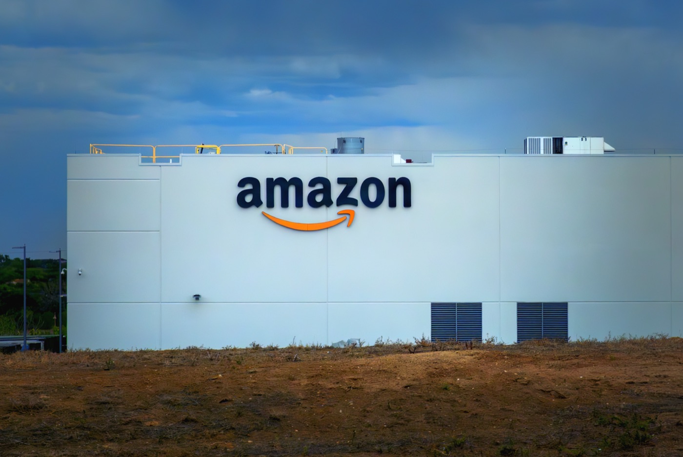 Large warehouse exterior wall with an Amazon logo — the type of Amazon fulfillment facility that VGT3 belongs to