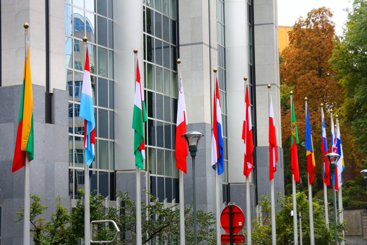 EU member state flags in front of the European Parliament in Brussels — the EU AI Act Annex III splits credit scoring as high-risk while excluding fraud detection