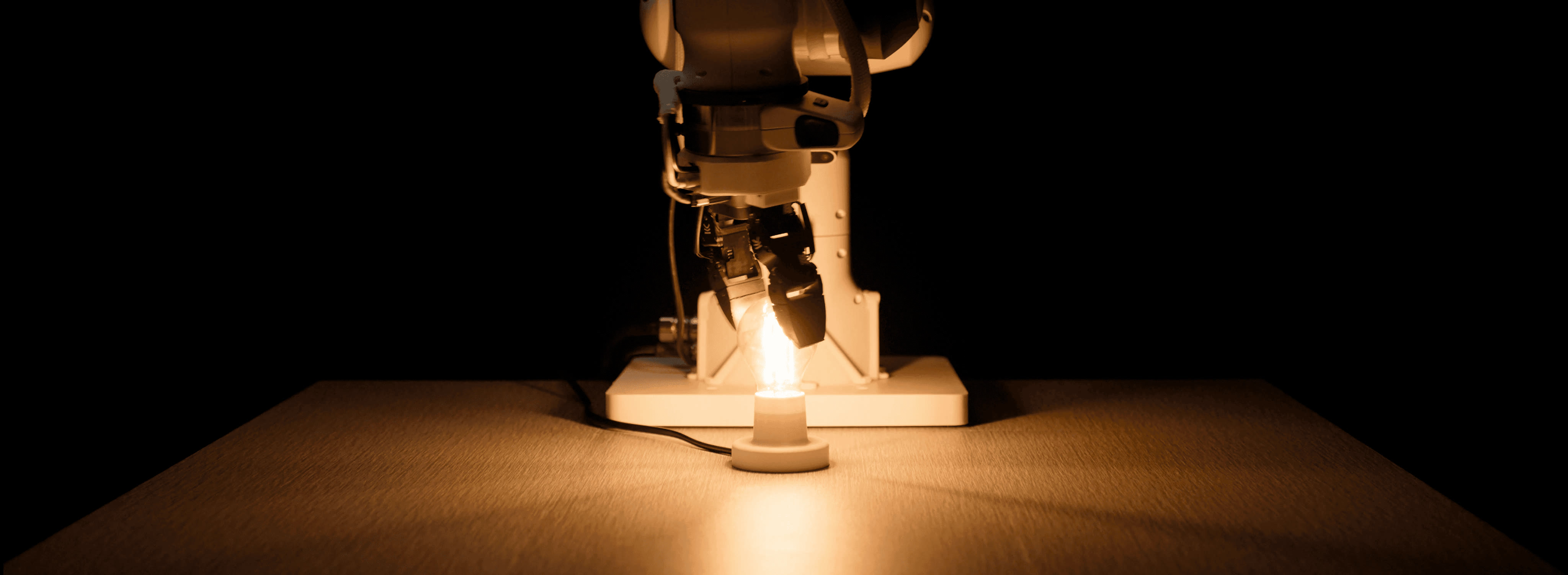 Eka's robot hand gripping a lit candle in a dark setting, illustrating manipulation guided by touch rather than sight