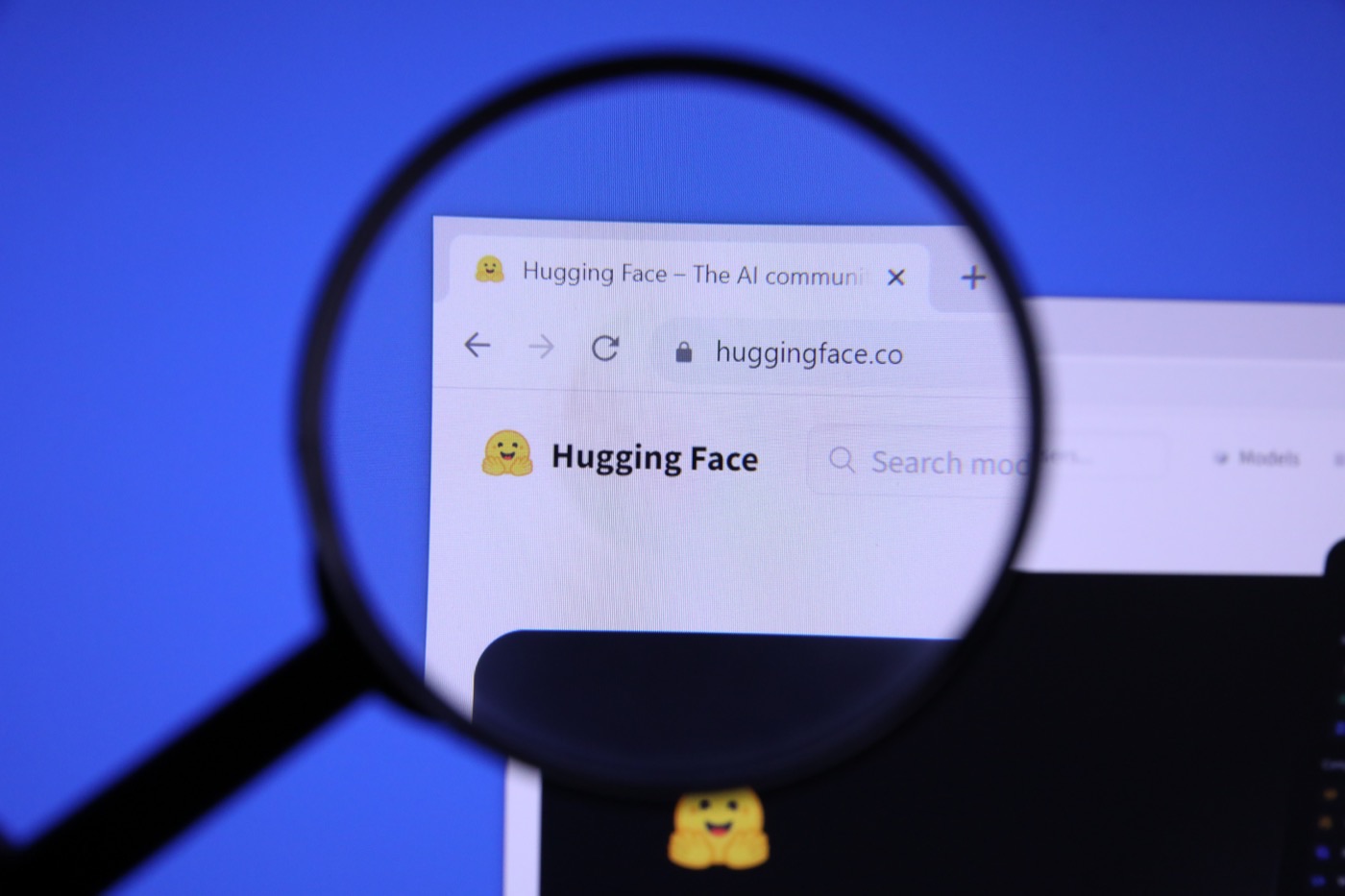 돋보기로 확대된 허깅페이스 홈페이지 화면, huggingface.co 주소창과 로고가 보인다