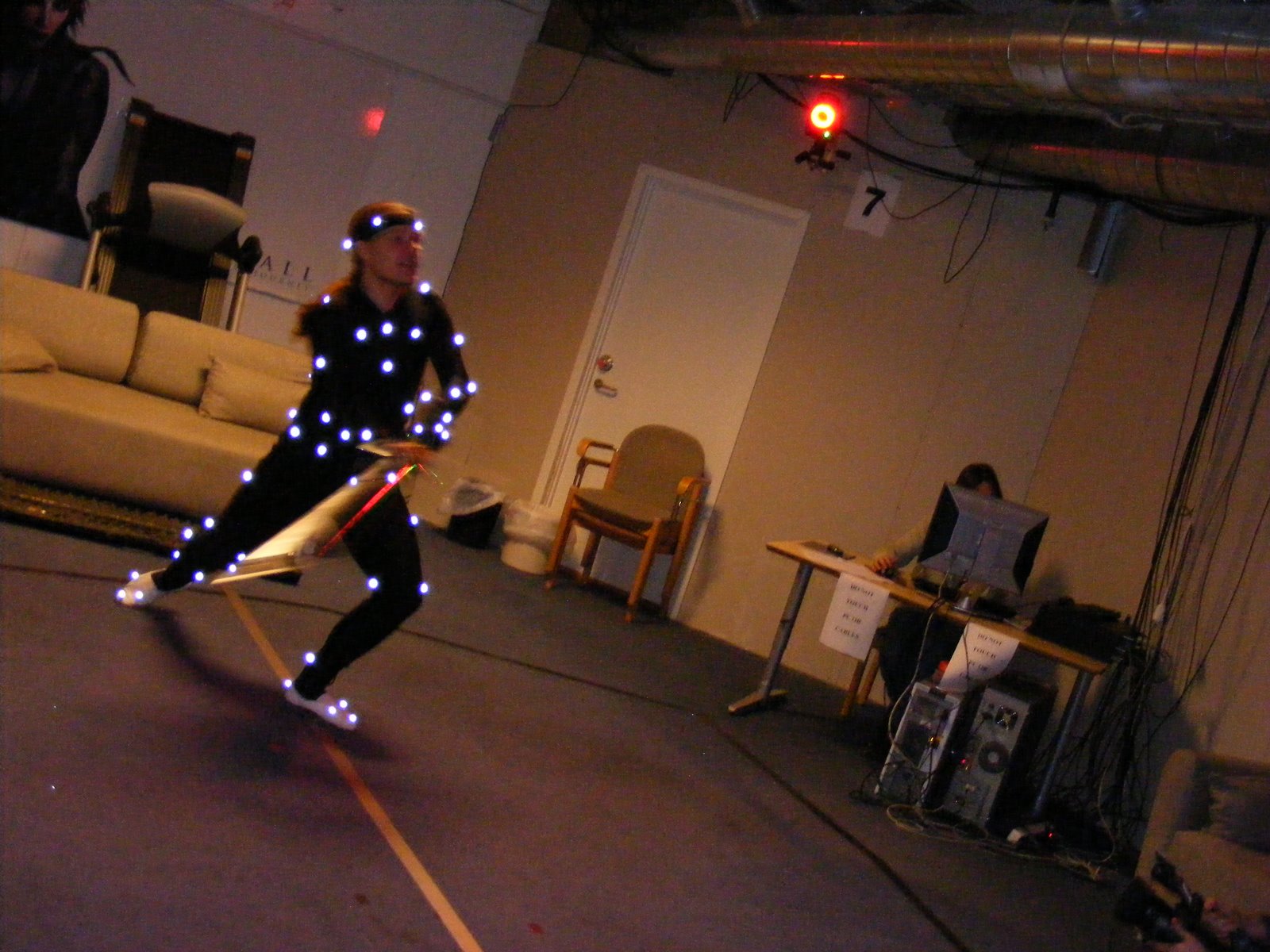 A professional motion capture studio with a performer in a marker suit being recorded by camera arrays