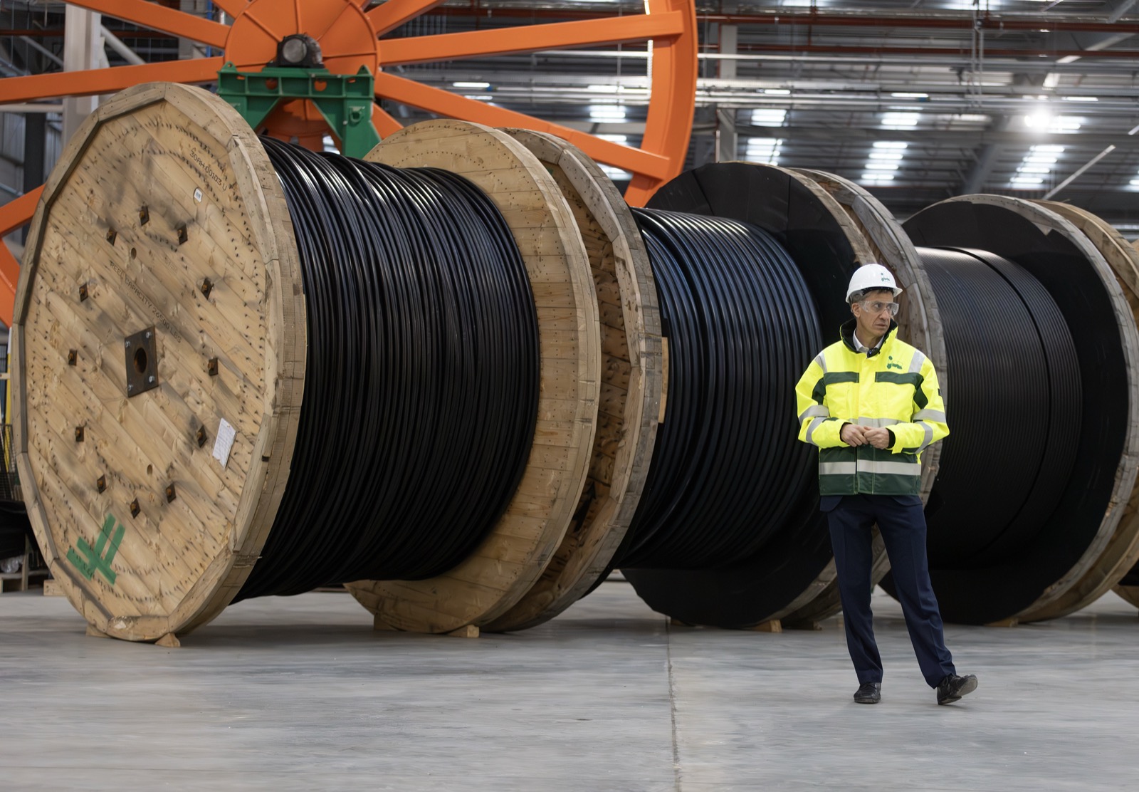 Large cable reels and a worker at a subsea power cable manufacturing plant