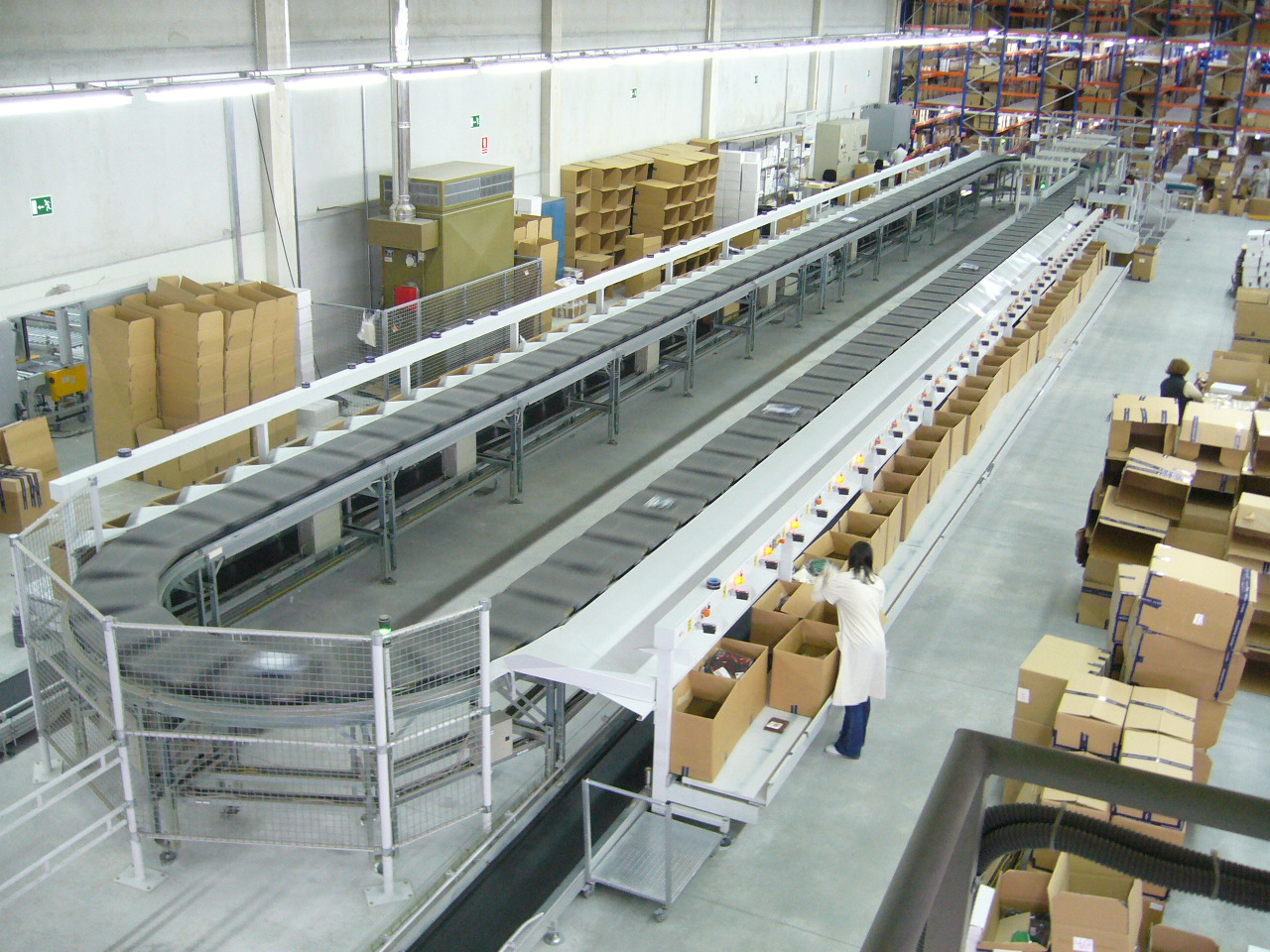 Warehouse cross-belt sorting conveyor with a worker manually loading parcels into chutes