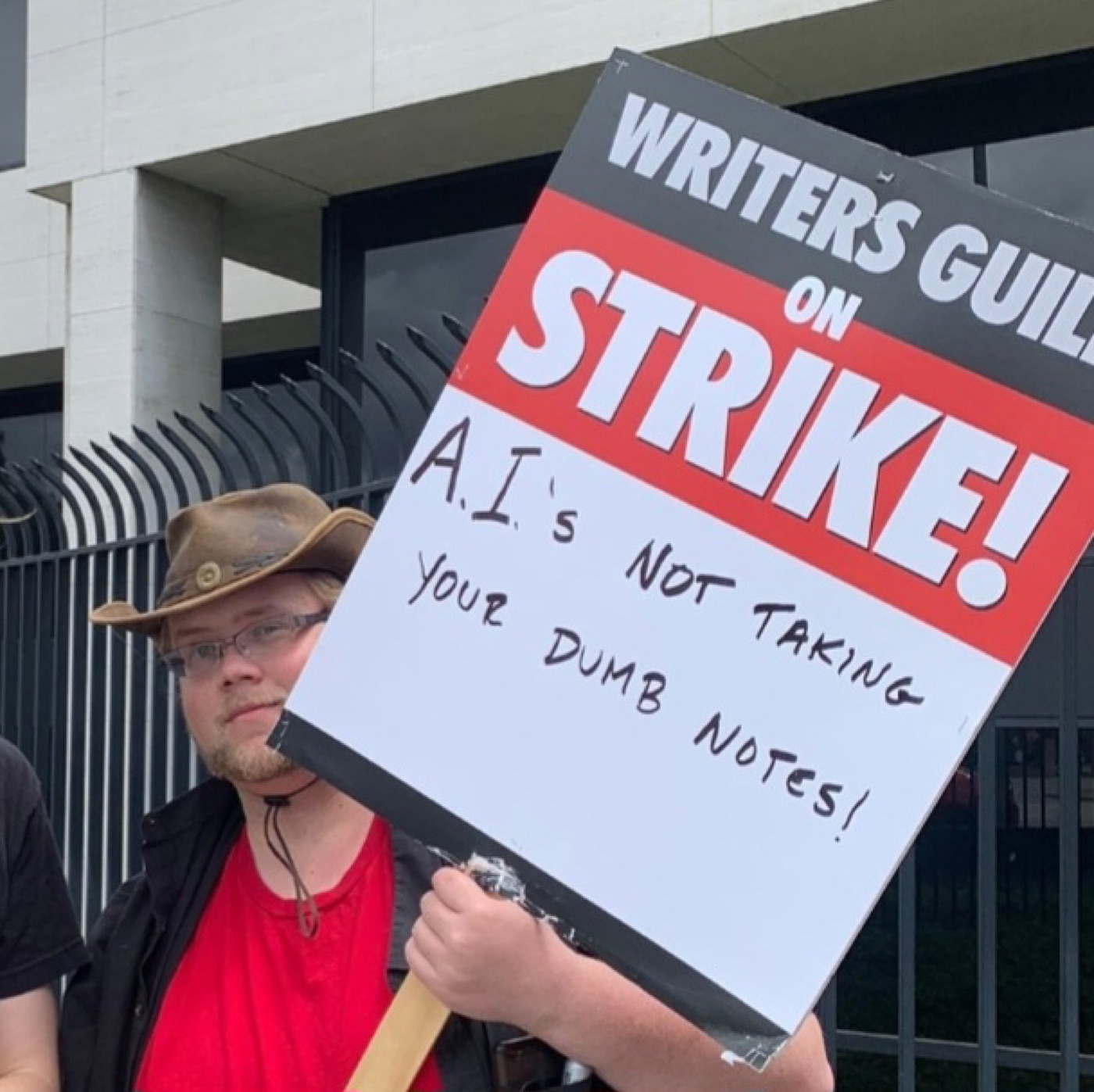 A Writers Guild member holds a picket sign reading 'A.I.'s not taking your dumb notes!' during the 2023 Hollywood strikes