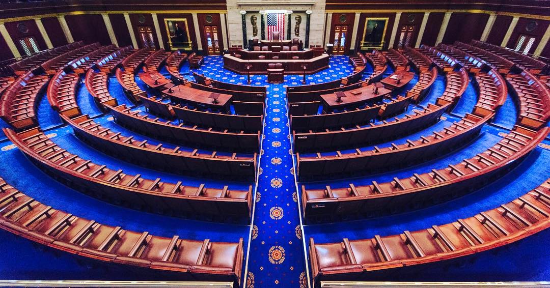 Interior of the US House of Representatives chamber, with seats arranged in a semicircle facing the rostrum