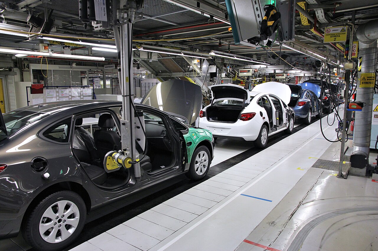 Car factory assembly line where a robotic arm helps assemble vehicle components in a controlled environment