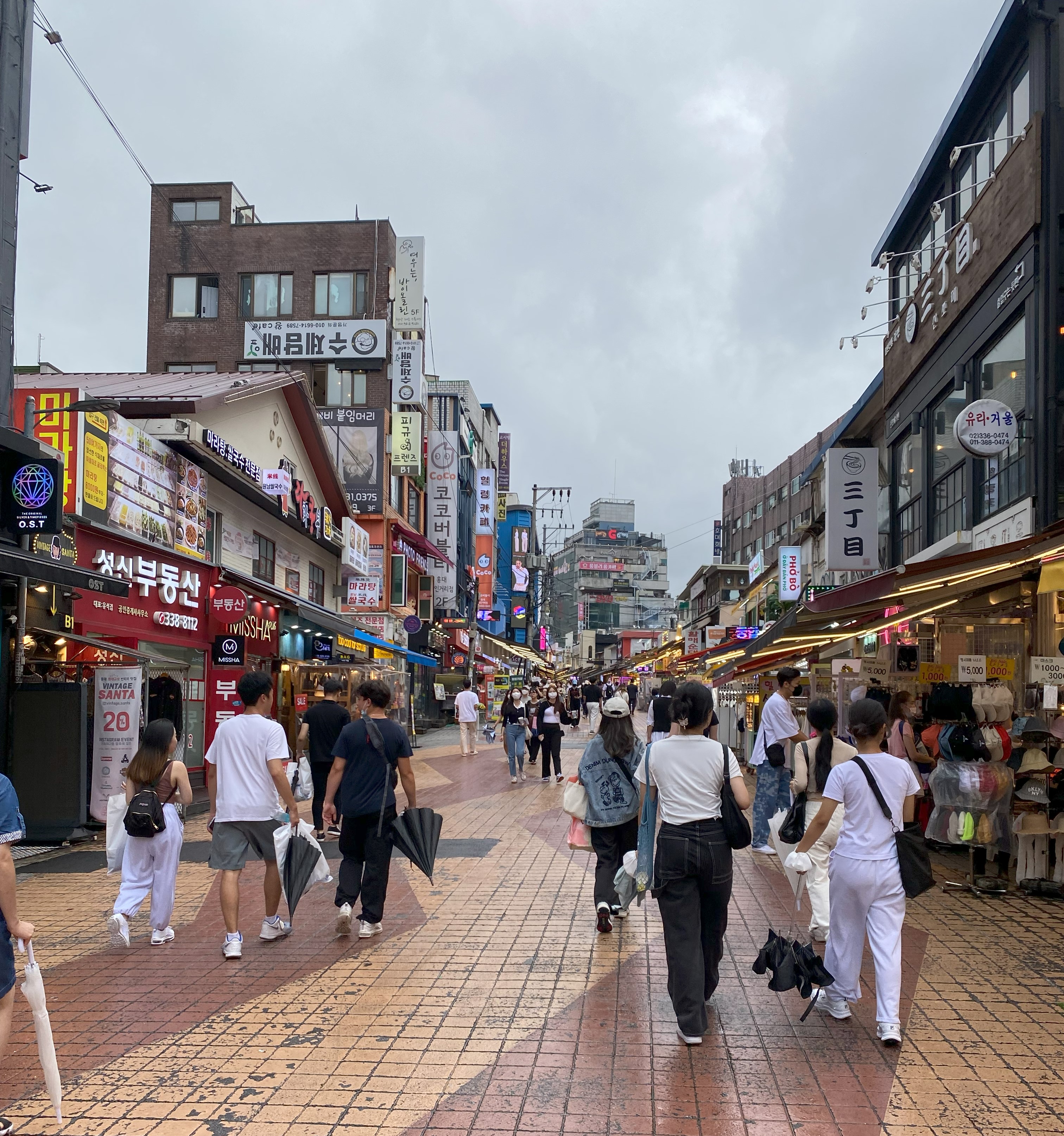 서울 홍대 거리 — 번화한 거리를 걷는 사람들과 실제 도시 맥락의 한국 패션